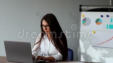 一幅美丽的欧洲女孩坐在办公室的<strong>笔记本</strong>电脑前的肖像，<strong>上面</strong>有一件白色衬衫，<strong>上面</strong>有图表和图片